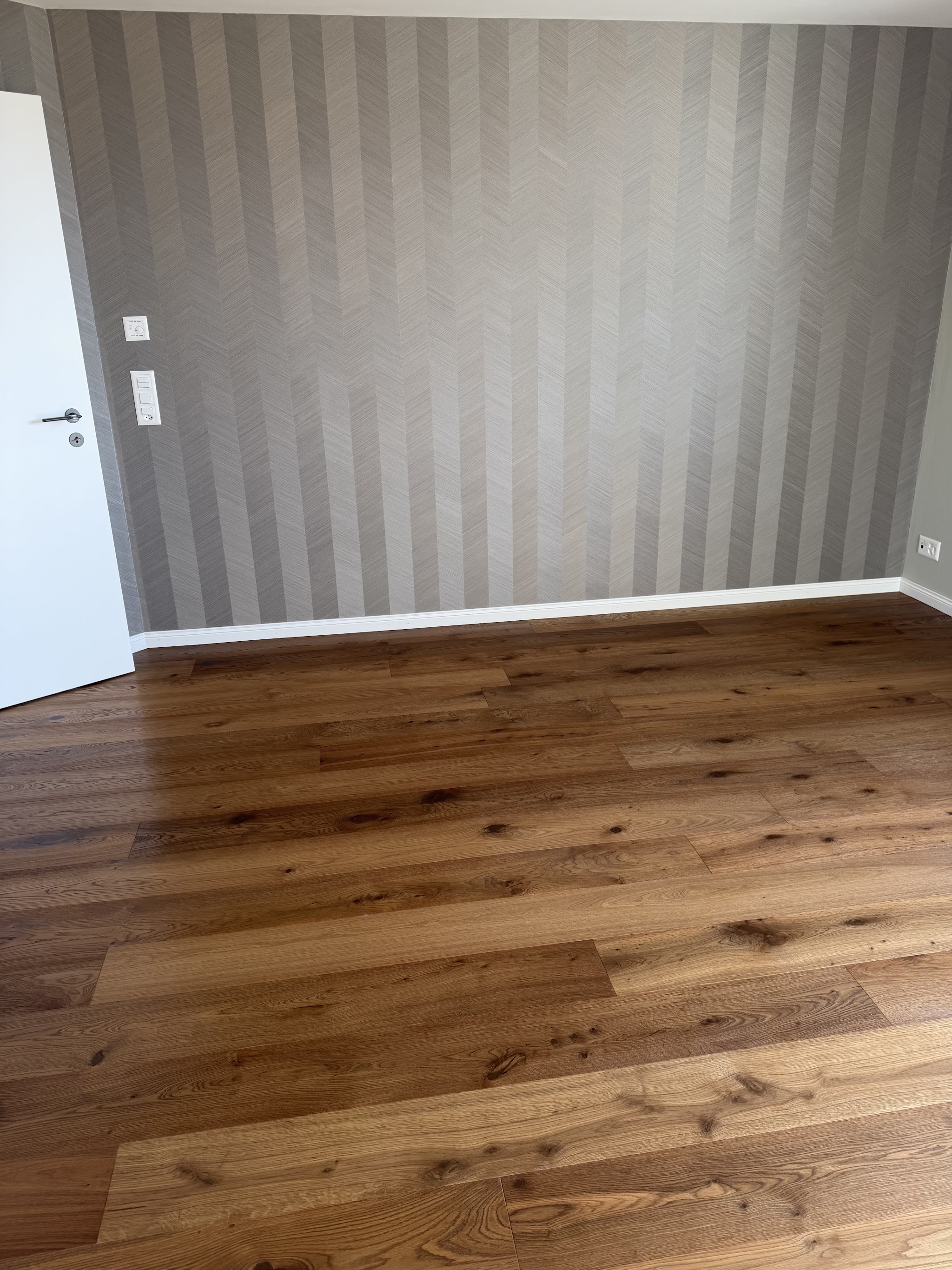 Gepflegter Eichenboden vor gestreifter Wand